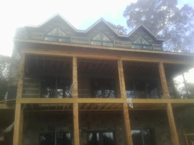 Dormers and porch framing on a large log home under construction — Roof Coating work by our crew in Otisville