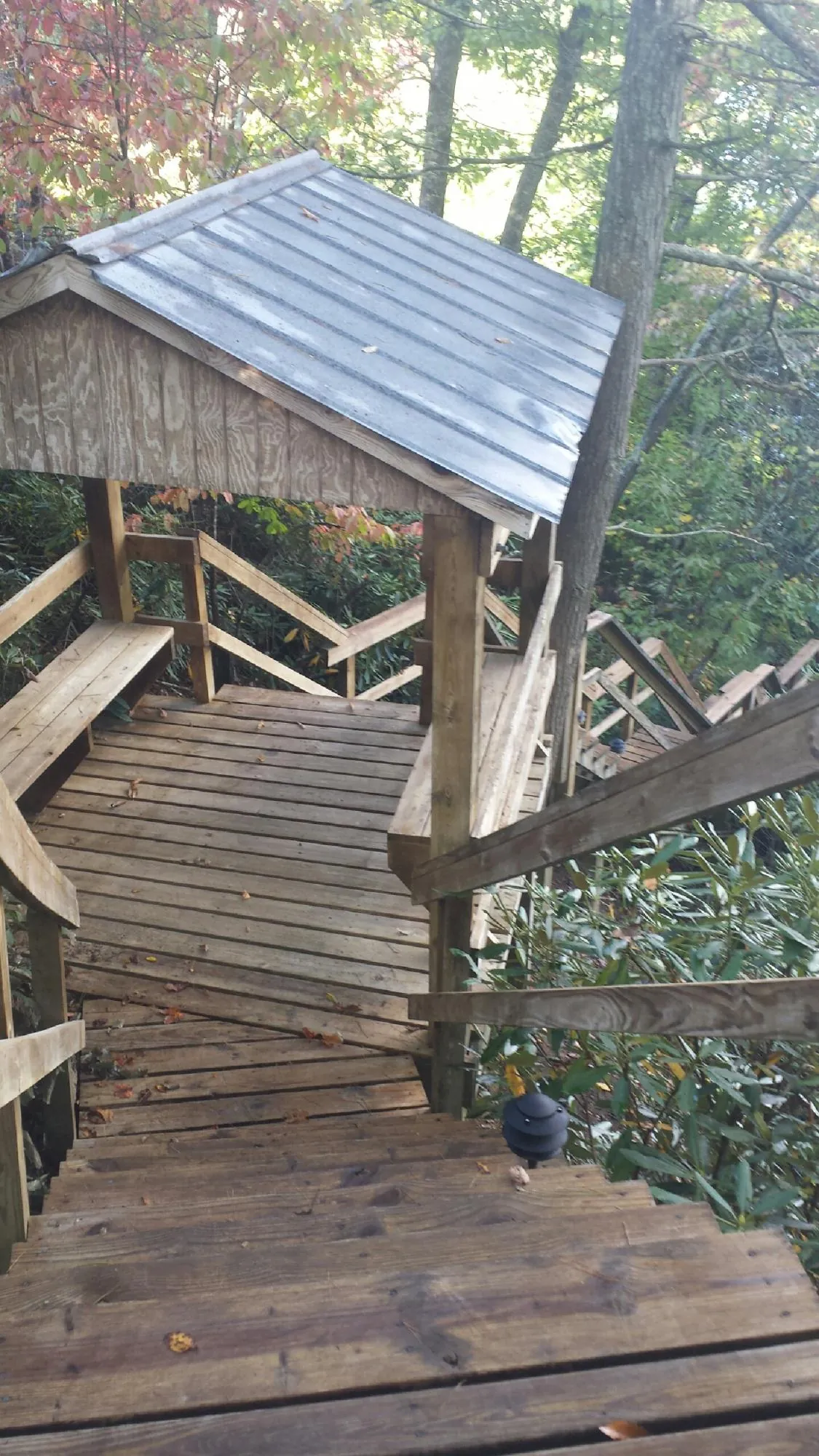 Metal roofed shelter over wooden steps on a wooded walkway — Skylight Repair & Installation work by our crew in Otisville