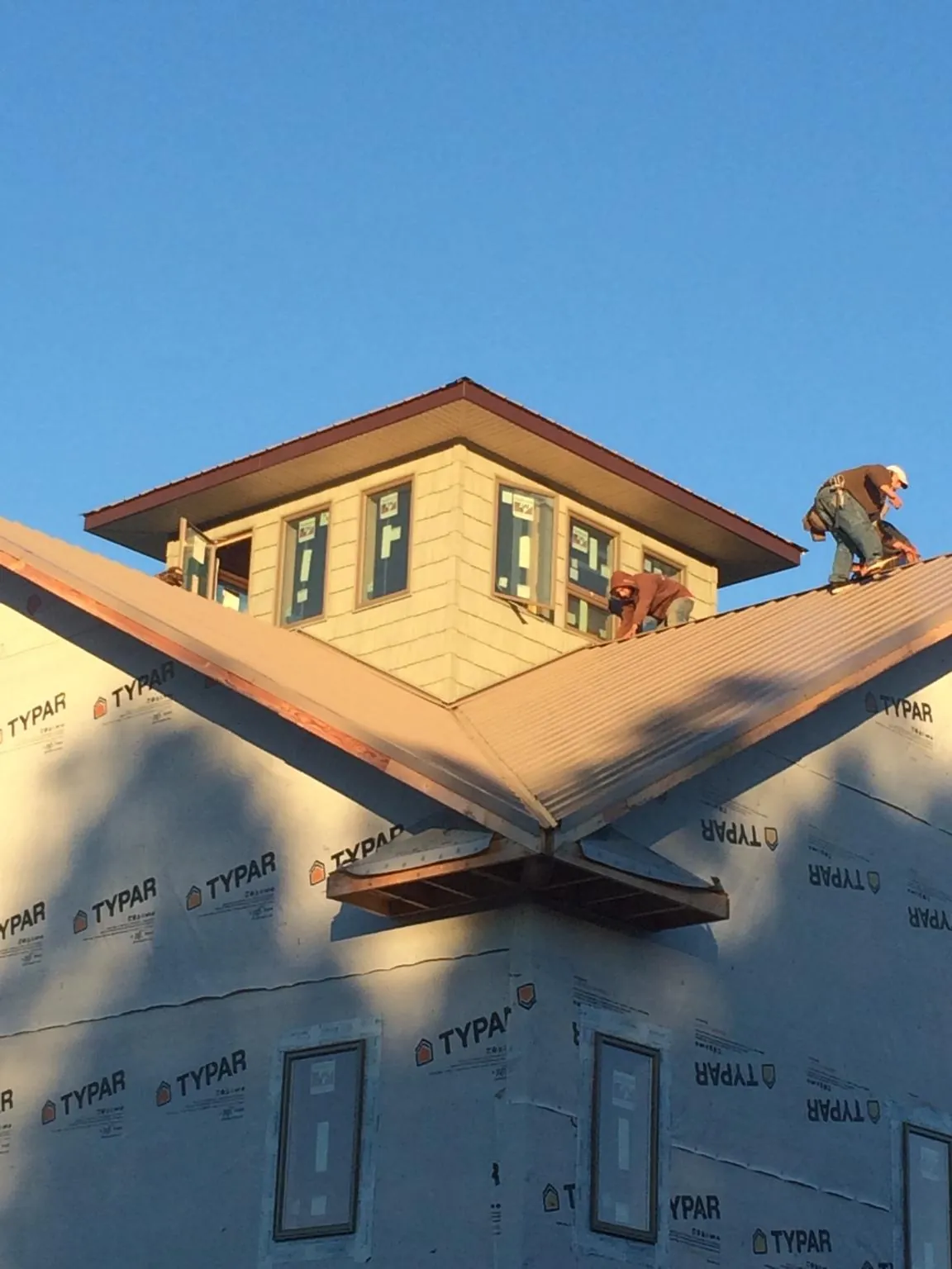 Roofers working around a rooftop cupola on a new metal roof at sunset — Roof Waterproofing in Otisville by Roofing Brothers
